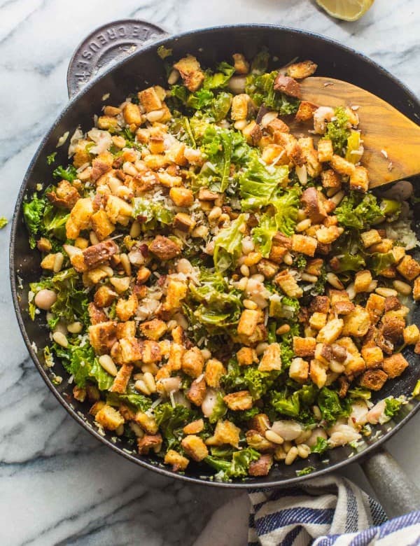 a skillet full of sautéd kale, pine nuts and gluten free croutons