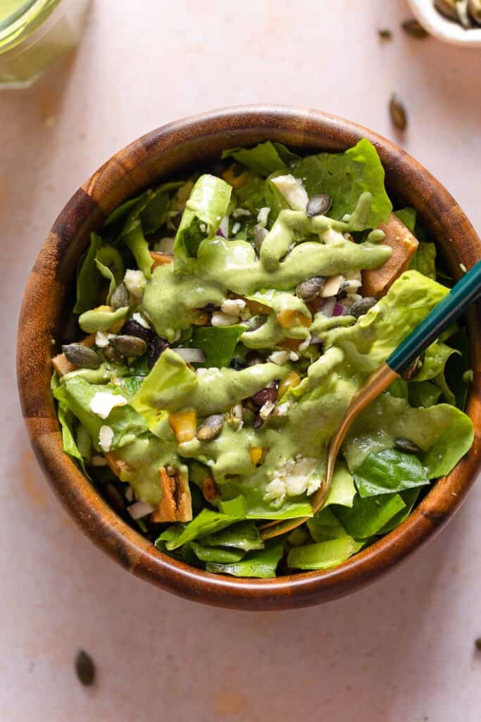 a salad topped with a creamy cilantro dressing