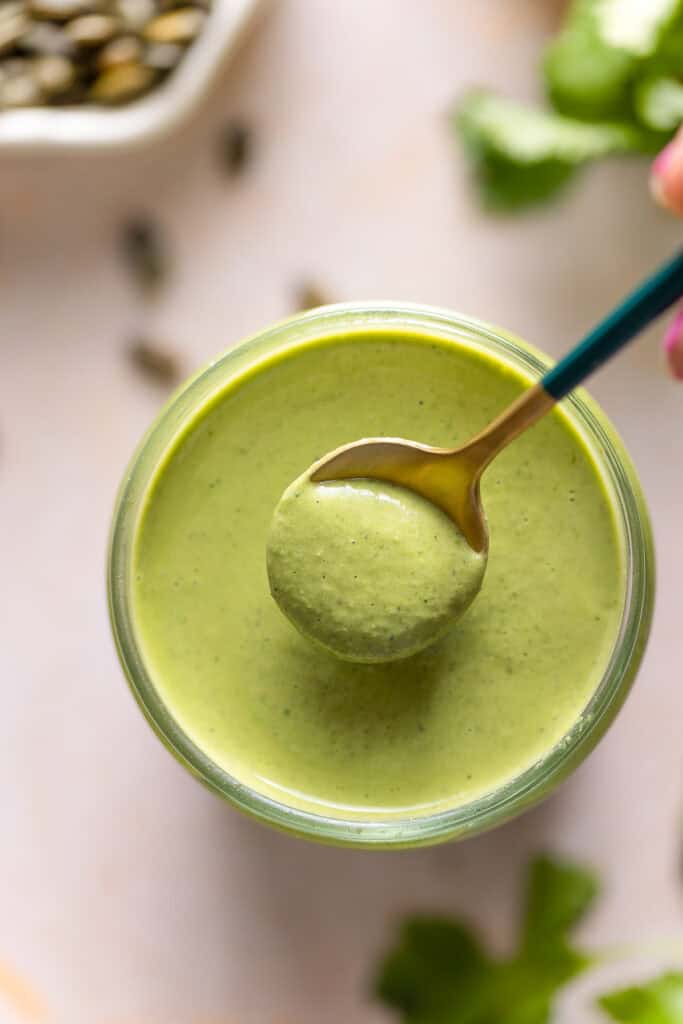 a small spoon full of cilantro pepita dressing over a jar