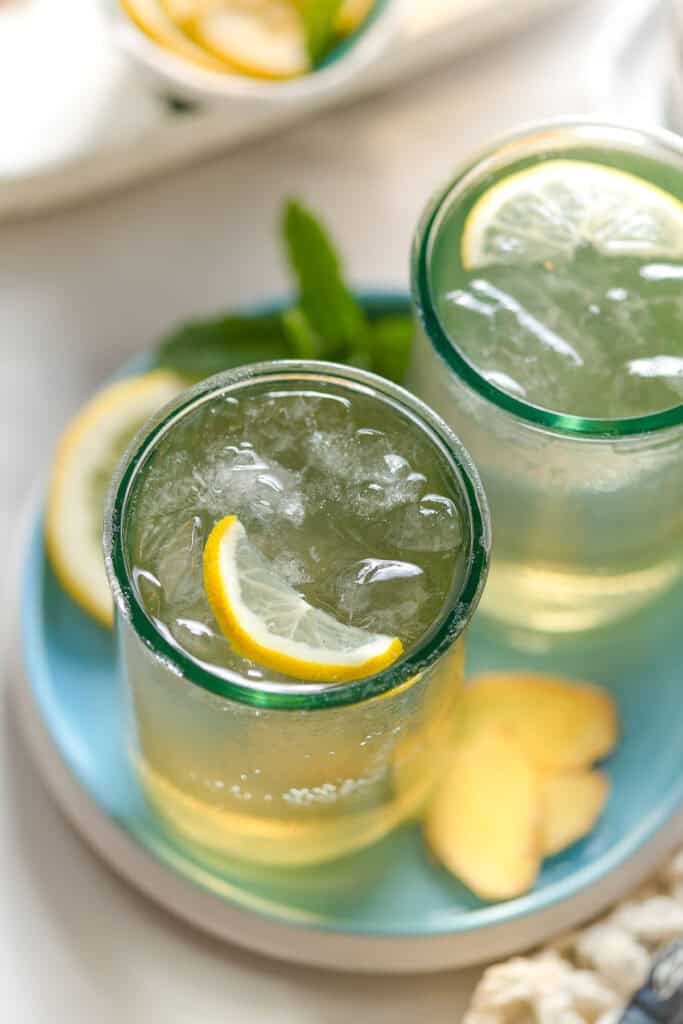 two glass of homemade switchel with crushed ice and lemon slices