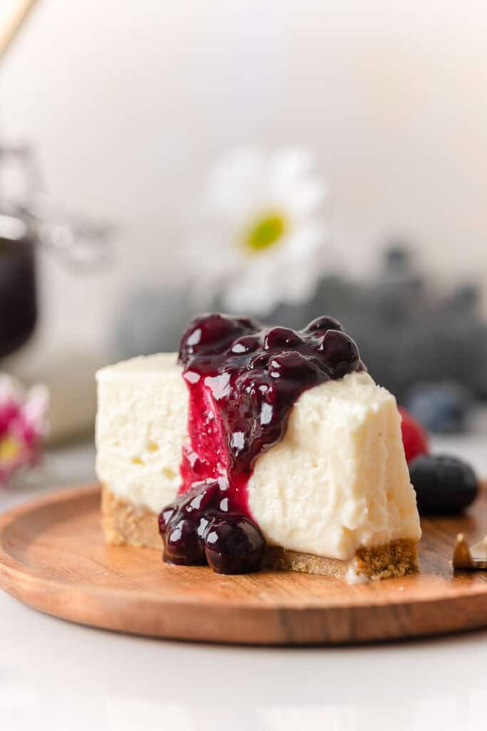 a slice of a no bake cheesecake with a blueberry sauce poured over the top and a bite take out of the cheesecake