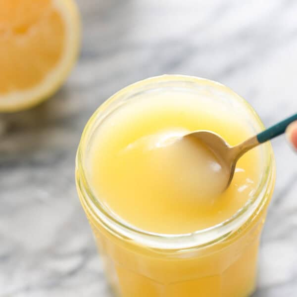 Homemade Vegan Lemon Curd in a jar stirred with a spoon