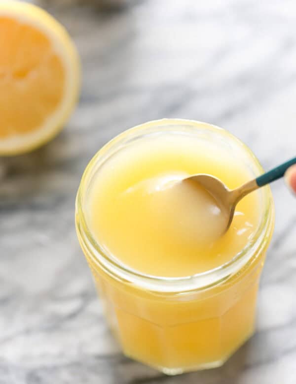 Homemade Vegan Lemon Curd in a jar stirred with a spoon