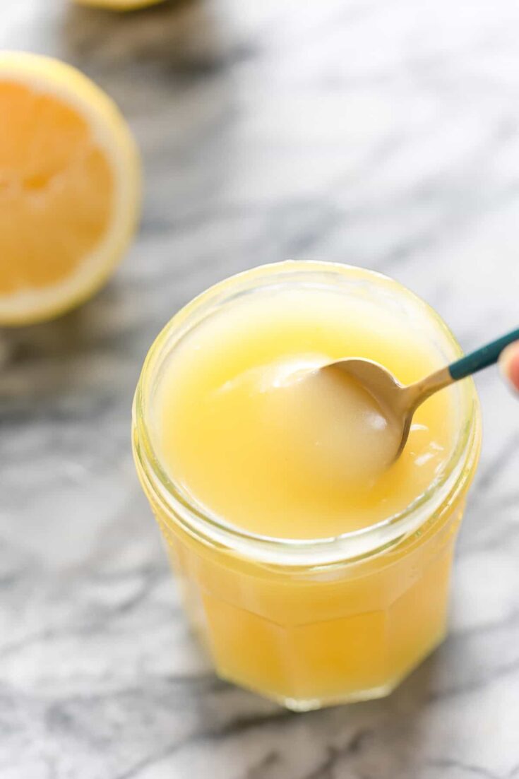 Homemade Vegan Lemon Curd in a jar stirred with a spoon