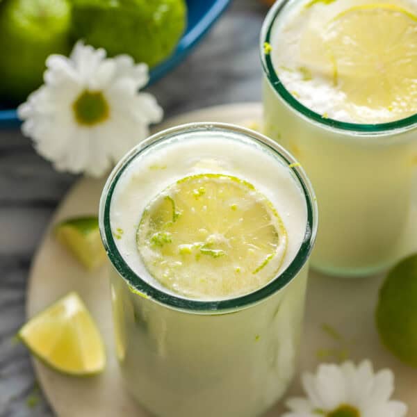 two glasses of Limonada Suíça also known as Brazilian Lemonade garnished with fresh lime slices