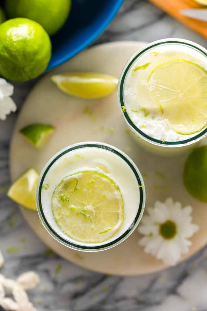 a couple of glasses full of Limonada Suíça also known as Brazilian Lemonade garnished with in a glass with a lime slice and lime zest