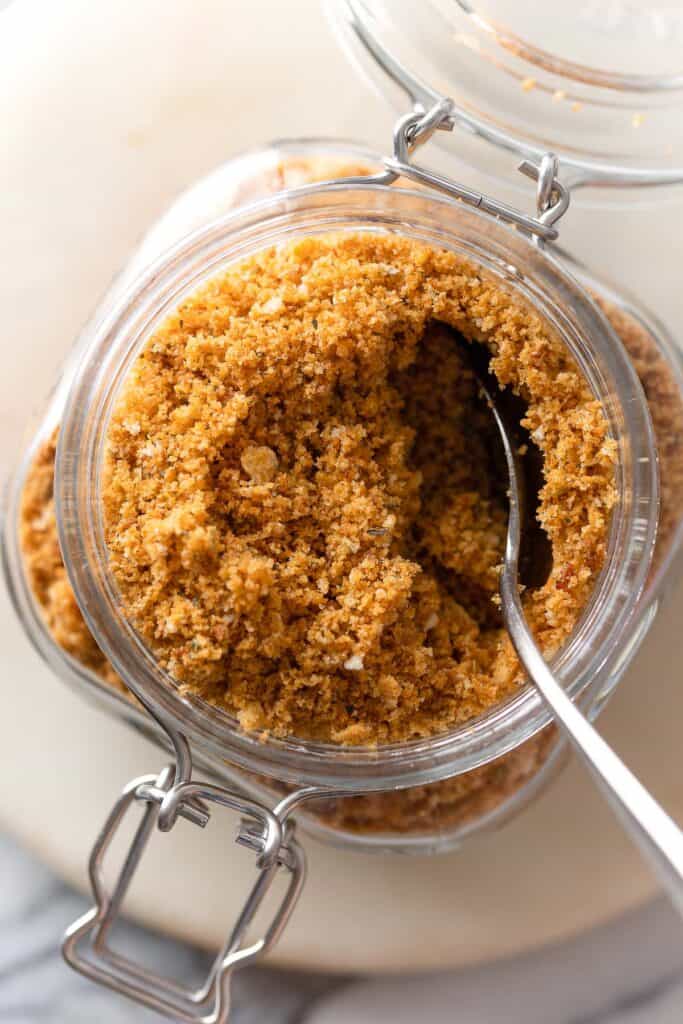 homemade gluten free breadcrumbs in a storage jar with a spoon viewed from above