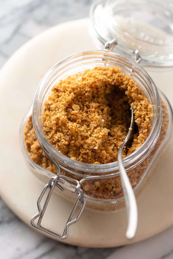 homemade gluten free breadcrumbs in a storage jar with a spoon viewed from above