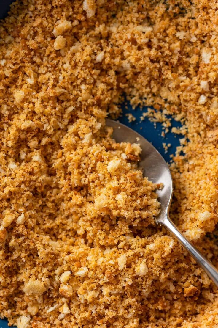 homemade gluten free breadcrumbs in a bowl with a spoon scooping some of the breadcrumbs up