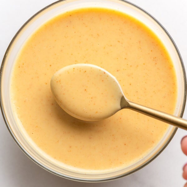 a small bowl full of Hot Honey Mustard Dipping Sauce with a spoon holding up some sauce