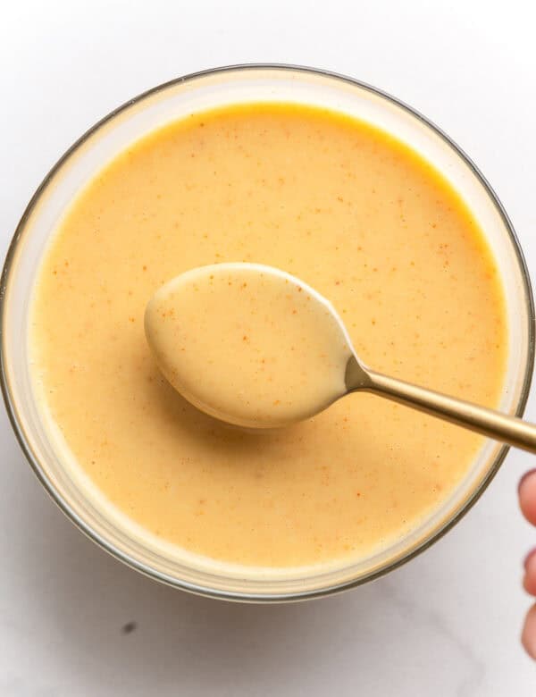 a small bowl full of Hot Honey Mustard Dipping Sauce with a spoon holding up some sauce