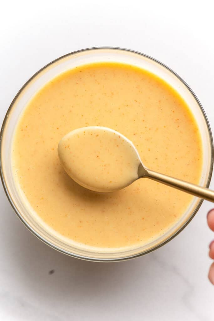 a small bowl full of Hot Honey Mustard Dipping Sauce with a spoon holding up some sauce