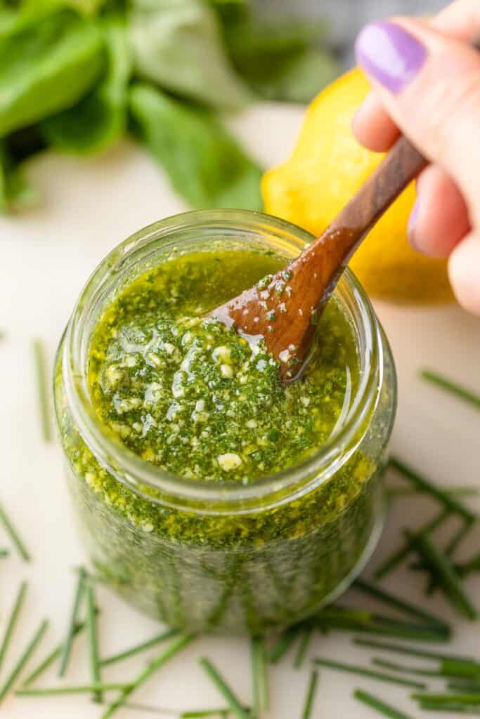 homemade low fodmap chive pesto in a jar with a spoon