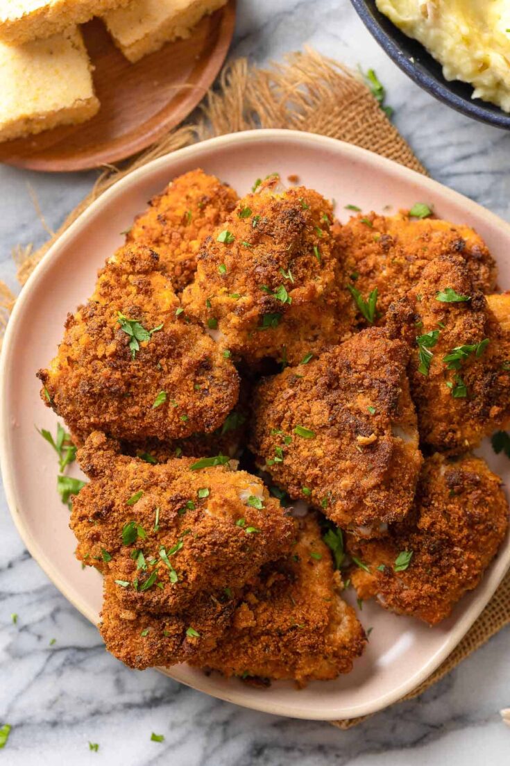 gluten free oven fried chicken thighs on a plate topped with fresh chopped parsley