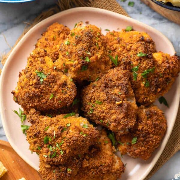 Oven Fried Chicken Thighs on a plate with fresh parsley on top with roasted okra, mashed potatoes and cornbread on the side