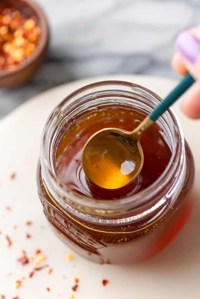 hot honey in a jar stirred by a spoon