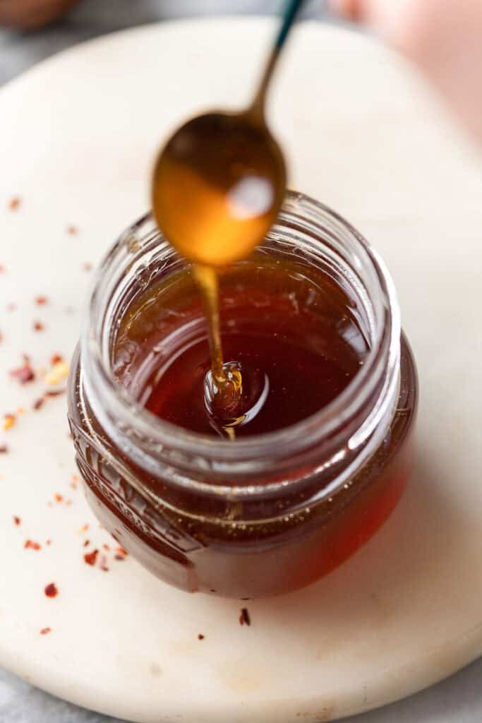 hot honey dripping off a spoon into a jar