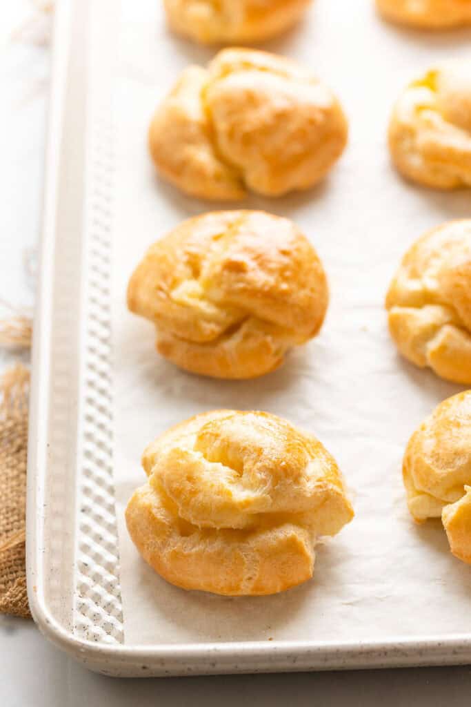 freshly baked gluten free choux buns on a baking sheet