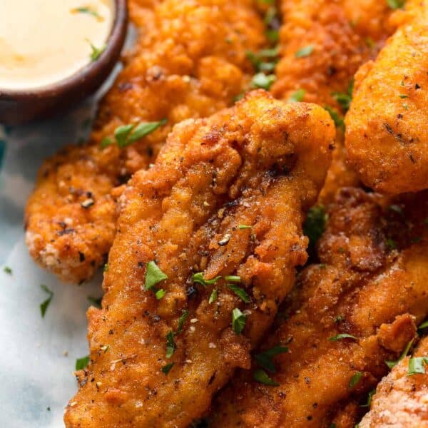 gluten free chicken tenders with fresh parsley sprinkled on top and a honey mustard dipping sauce on the side