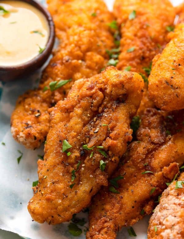 gluten free chicken tenders with fresh parsley sprinkled on top and a honey mustard dipping sauce on the side