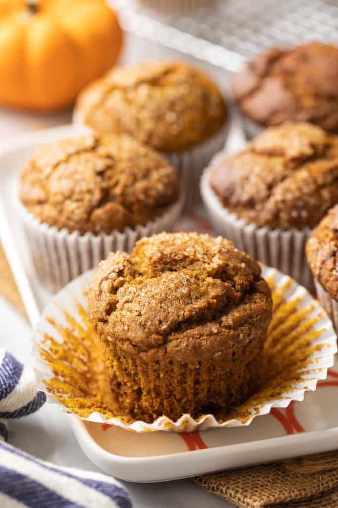 Gluten Free Pumpkin Muffins with the paper line pulled off one of the muffins 