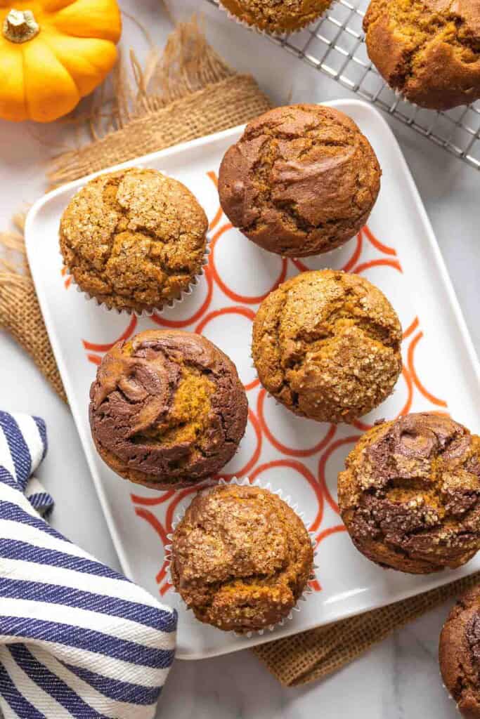 A plate full of 6 gluten free pumpkin muffins; some muffins have a nutella swirl on top and some muffins are sprinkled with coarse sugar