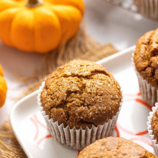 Gluten Free Pumpkin Muffins on a serving plate with a little pumpkin