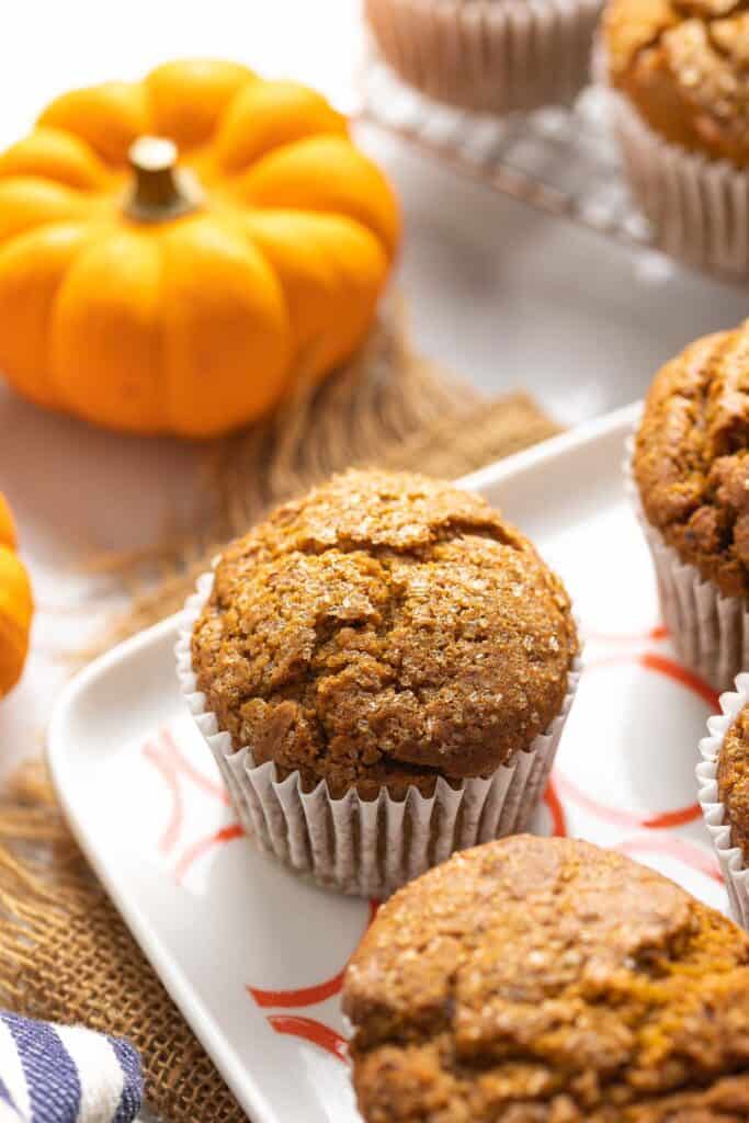 Gluten Free Pumpkin Muffins on a serving plate with a little pumpkin