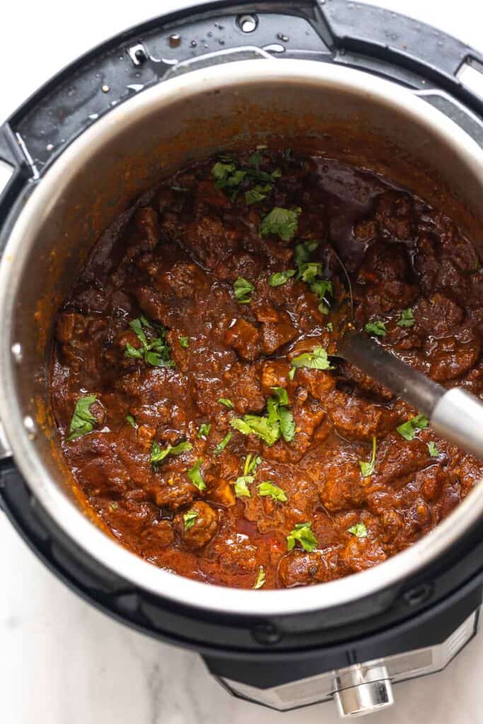 an instant pot full of carne desmechada with fresh cilantro on top