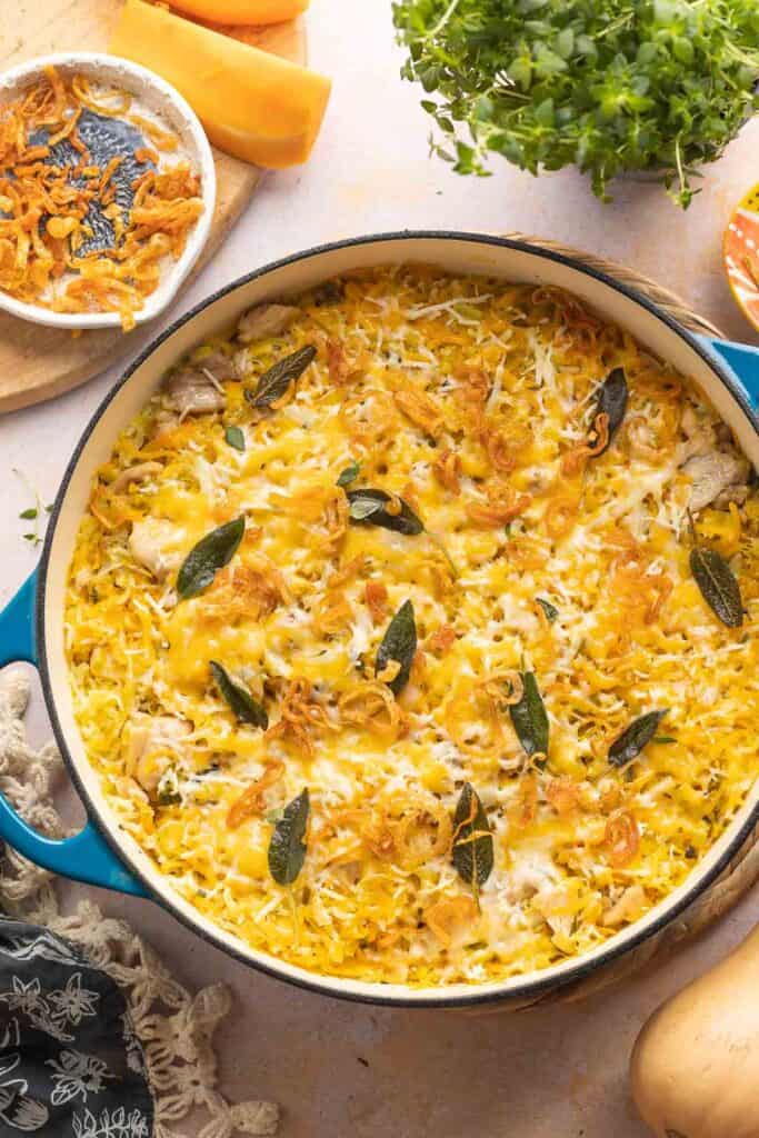 One pot Butternut Squash Chicken & Rice in a casserole dish topped with fried sage, fried shallots, and fresh thyme