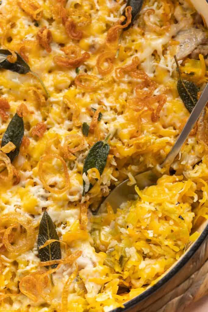 a spoonful of Cheesy Chicken & Butternut Squash Rice with crispy fried shallots and fried sage on top