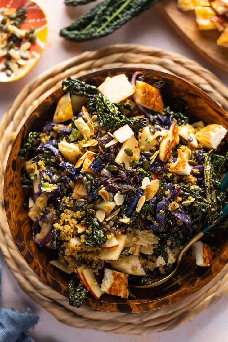 Roasted Cabbage and Kale Salad with Crispy Quinoa in a salad bowl with apples, fried halloumi, pumpkin seeds and almond slices