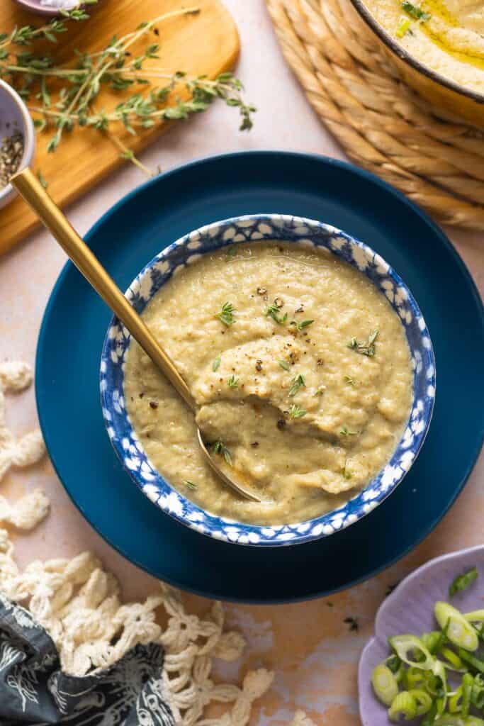 roasted cauliflower and garlic soup in a bowl with fresh thyme leaves on top