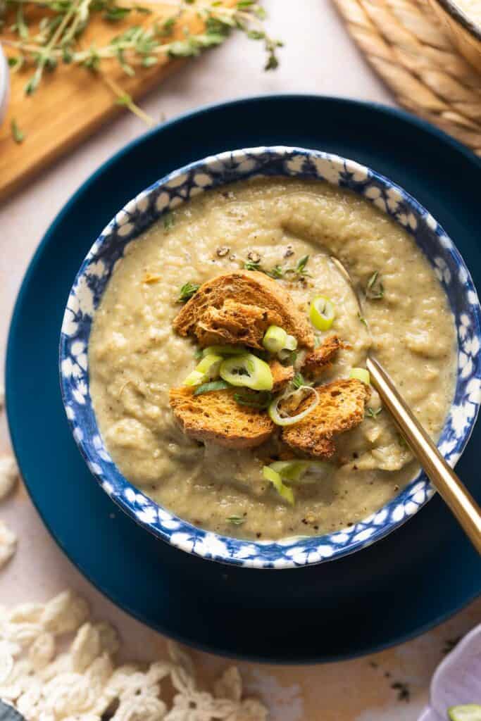 roasted cauliflower and garlic soup in a bowl with homemade gluten free croutons on top with slices green onions