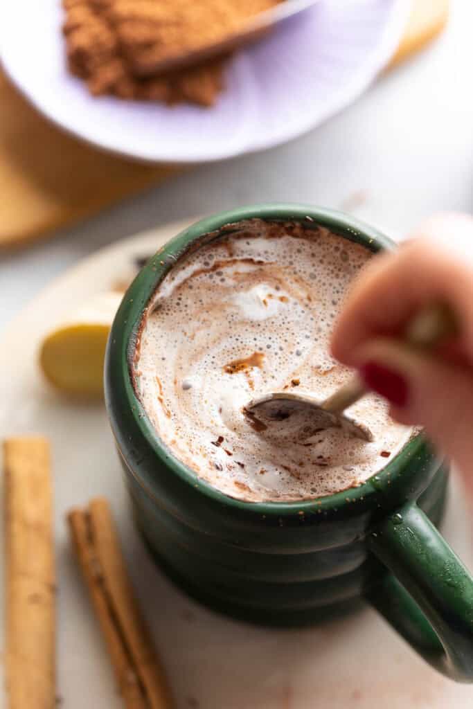 a spoon stirring a mug on homemade spiced chai hot chocolate