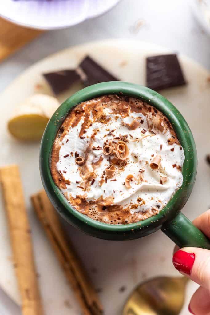 a mug of chai hot chocolate with whipped cream and chocolate shavings on top