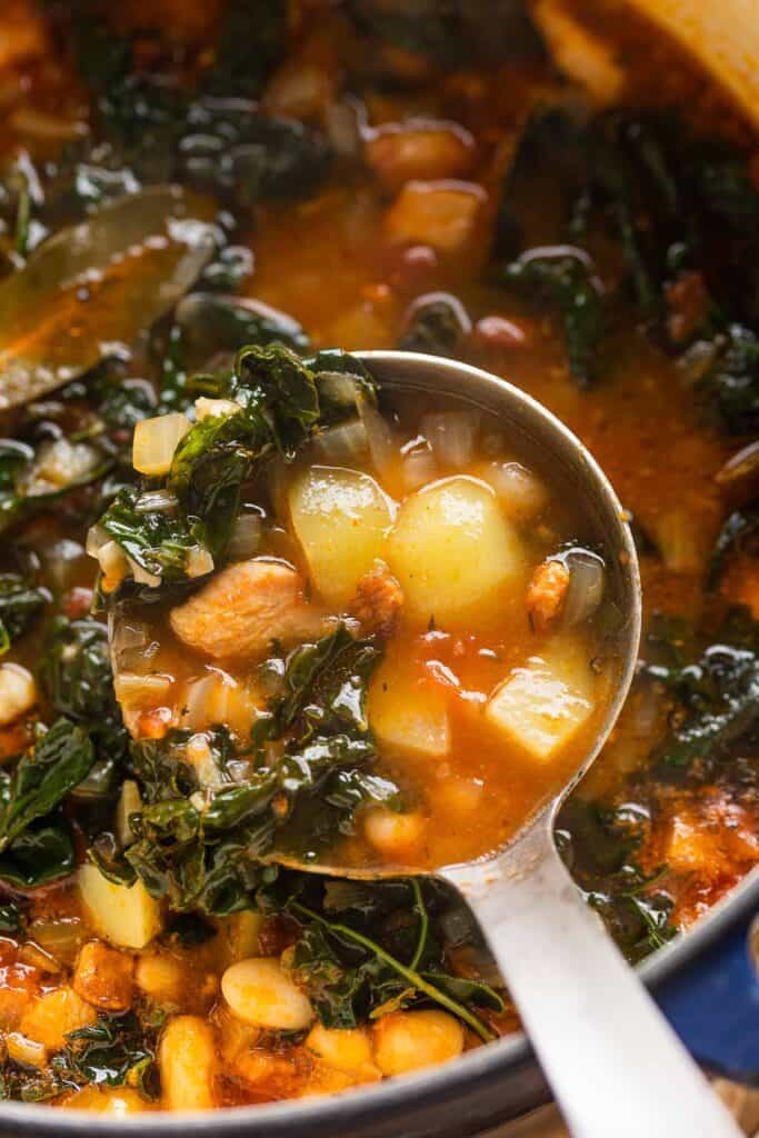 a soup ladle full of A large soup pot full of Bacon Kale Bean Soup 