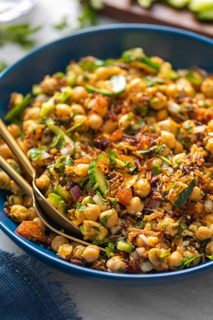 A salad bowl full of diced cucumber, red onion, chickpeas and baked crispy rice tossed in a herb-lemon vinaigrette. 