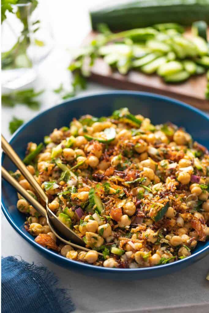 Crispy Rice Salad with Lemony Chickpeas & Cucumber in a salad bowl with serving spoons.