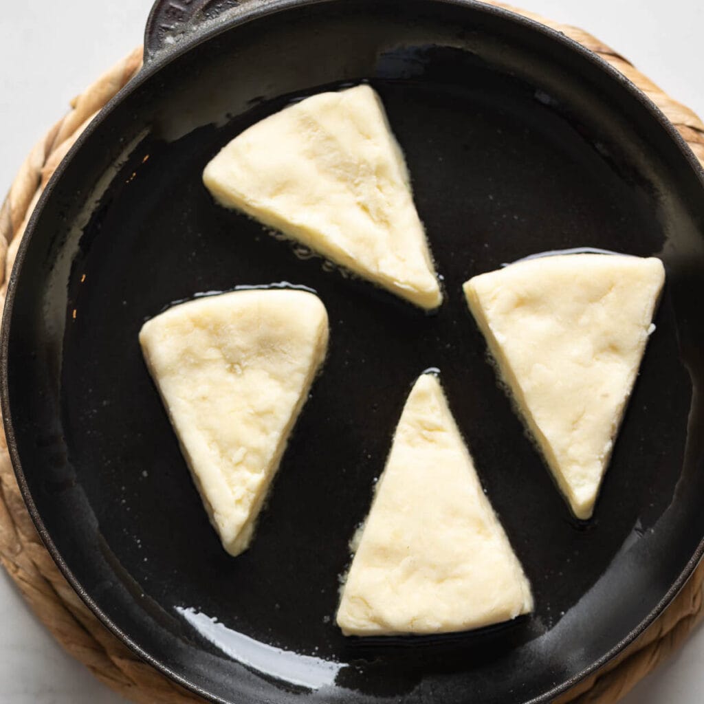 Irish Potato Bread (potato farls) cooking in a cast iron pan.