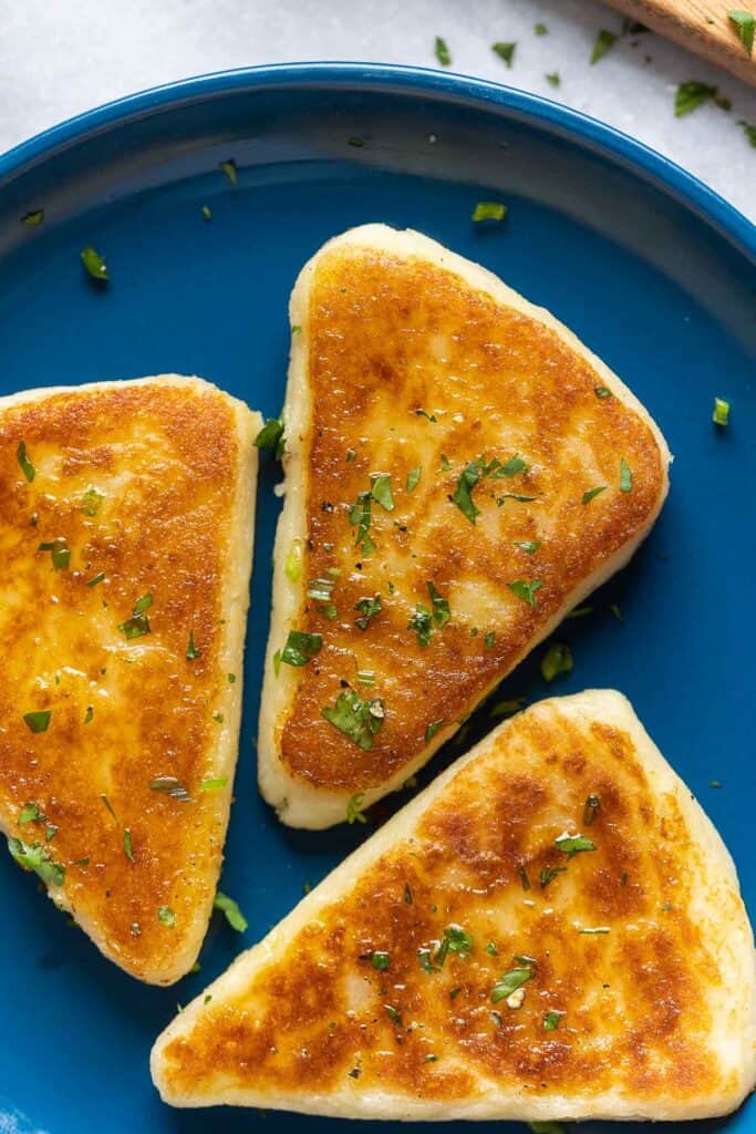 A plate with three pieces of Irish Potato Bread with fresh chopped parsley and chives on top.