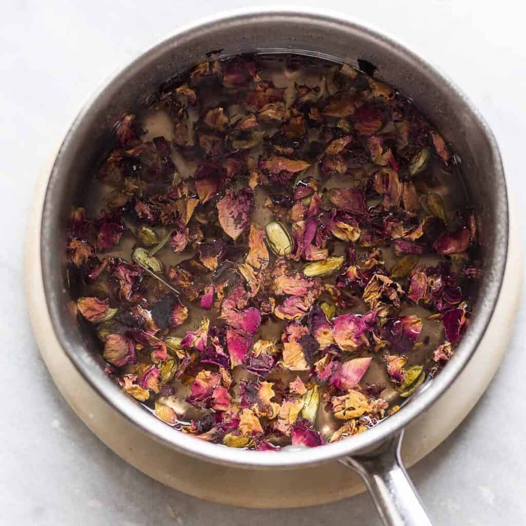 A saucepan full of rose petals, cardamom and sugar.