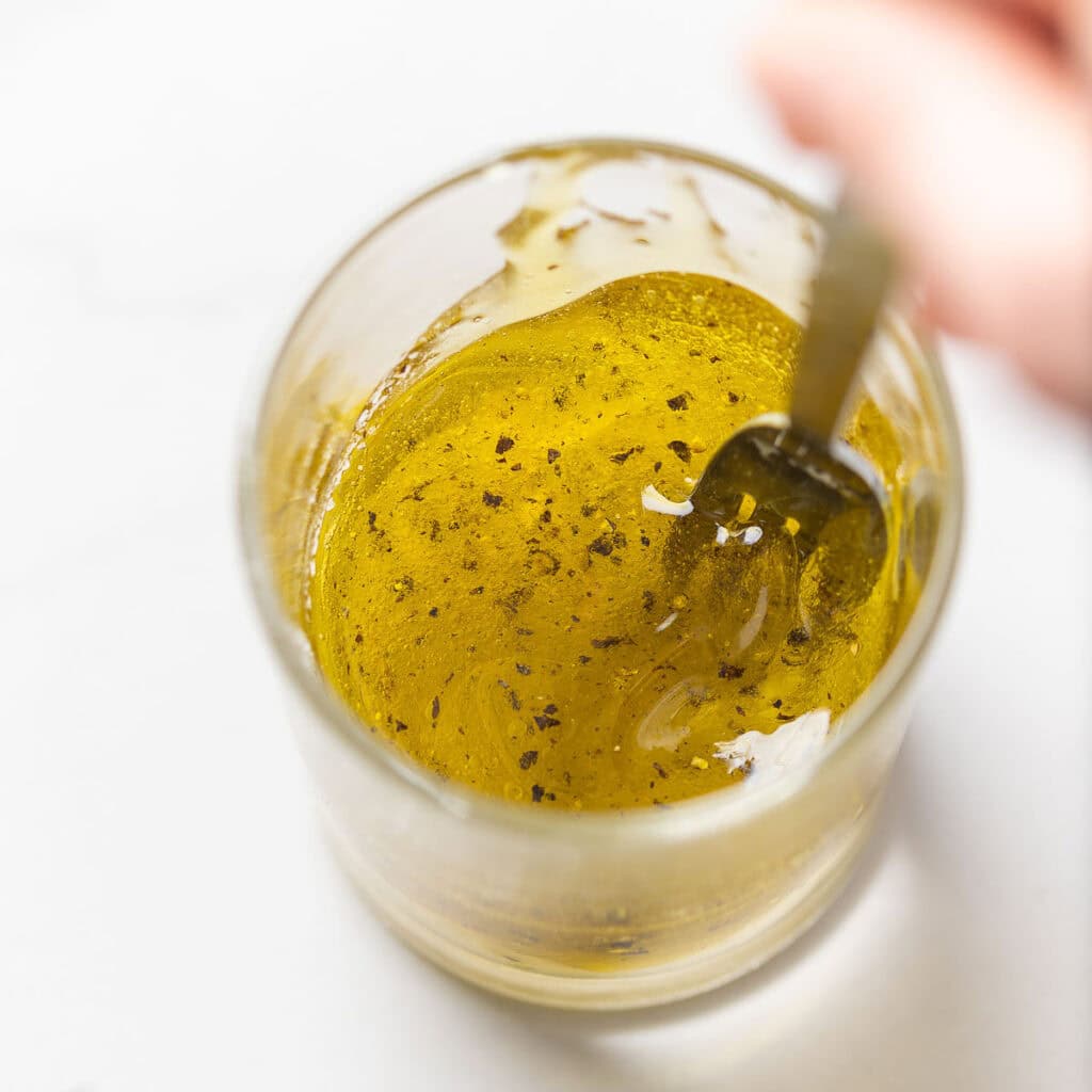 A fork whisking together a lemon-garlic vinaigrette. 