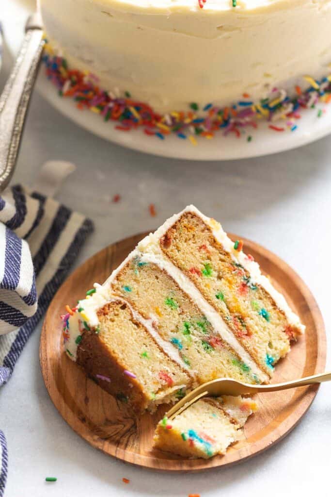 A slice of gluten free funfetti cake on a plate with a fork.