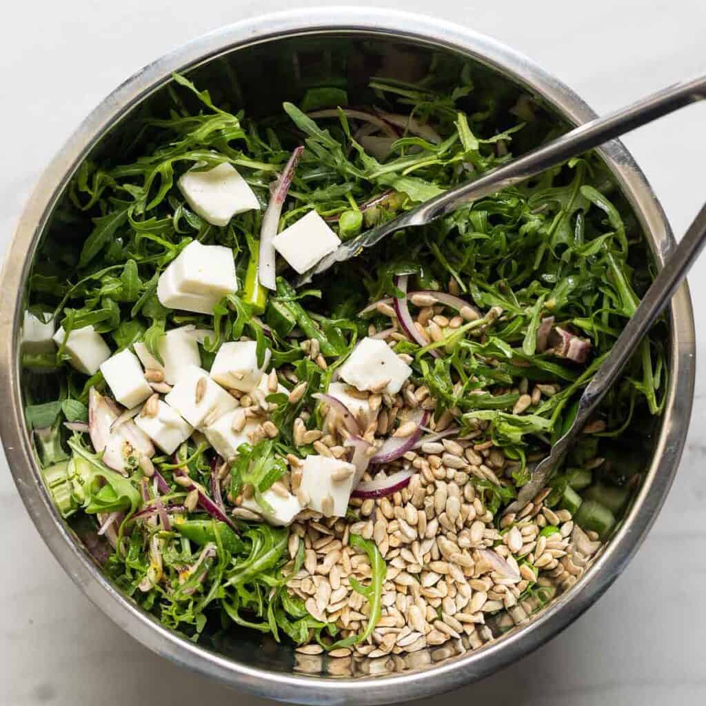 Blanched veggies, arugula, mozzarella, sunflower seeds, onion and cucumber in a large salad bowl.