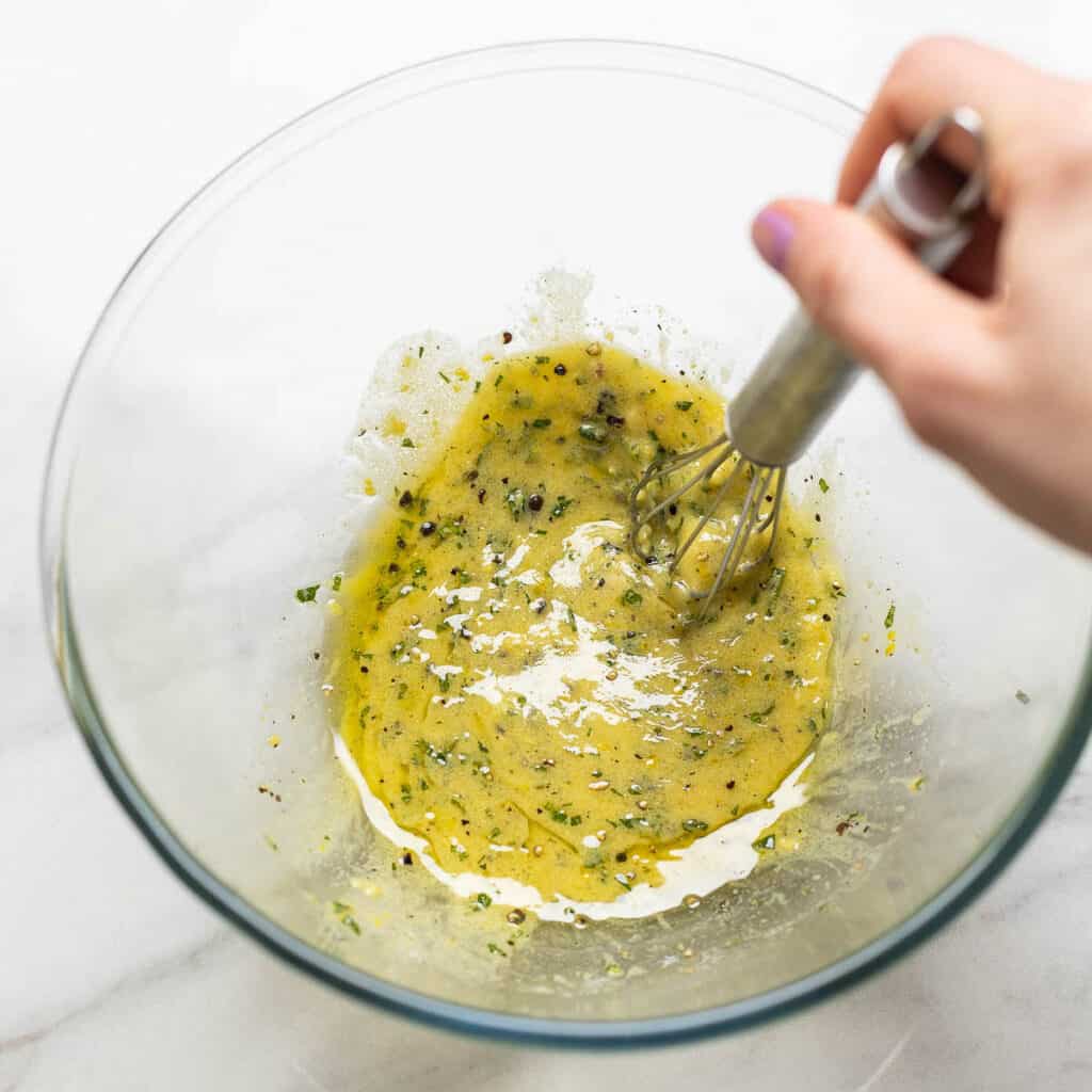 A lemon-dijon vinaigrette whisking together in a bowl.