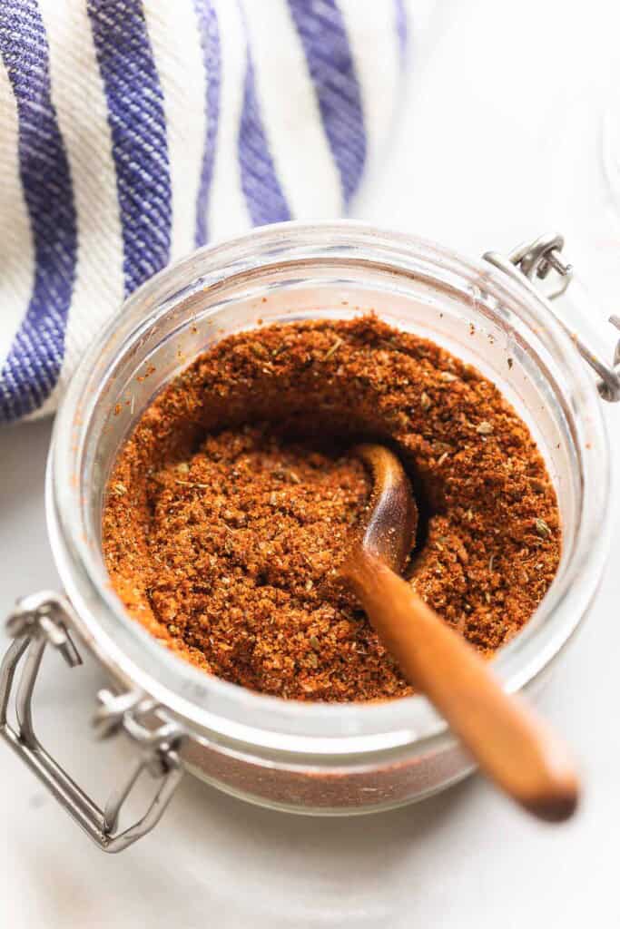 Homemade Low Fodmap Fajita seasoning in a small storage jar with a wooden spoon inside