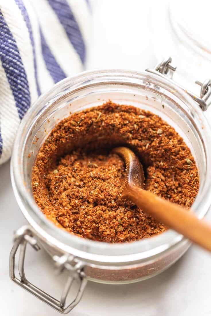 Homemade Low Fodmap Fajita Seasoning mixed in a small storage jar with a wooden spoon.