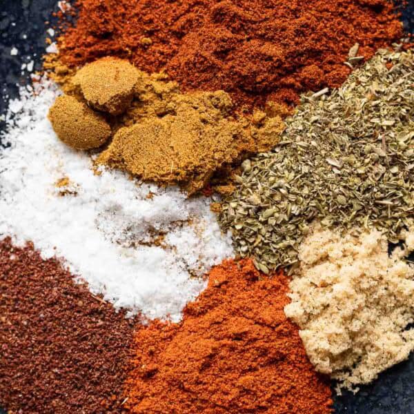 Chili powder, paprika, cumin, oregano, salt and brown sugar on a plate on a plate