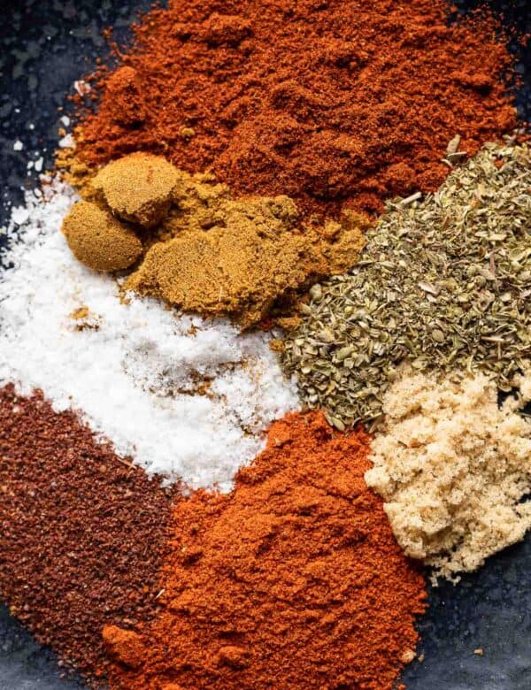 Chili powder, paprika, cumin, oregano, salt and brown sugar on a plate on a plate